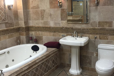 Example of a mid-sized transitional master beige tile and travertine tile marble floor and beige floor drop-in bathtub design in New York with a pedestal sink, a one-piece toilet and beige walls