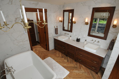 他の地域にあるトラディショナルスタイルのおしゃれな浴室 (ベッセル式洗面器、落し込みパネル扉のキャビネット、濃色木目調キャビネット、置き型浴槽、白い壁) の写真