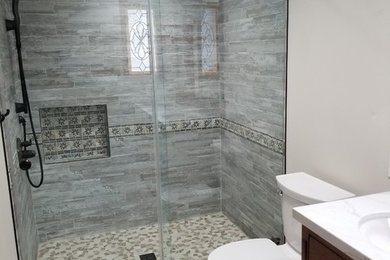 Example of a mid-sized minimalist bamboo floor bathroom design in Los Angeles with recessed-panel cabinets, black cabinets, a one-piece toilet, blue walls, an integrated sink and solid surface countertops