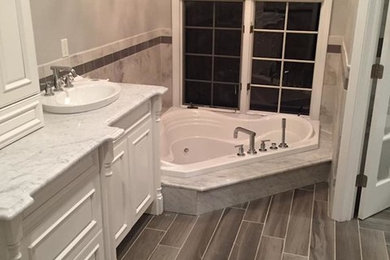 Large master white tile and marble tile gray floor drop-in bathtub photo in Bridgeport with recessed-panel cabinets, white cabinets, gray walls, a drop-in sink and marble countertops