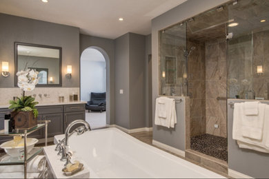 This is an example of a medium sized traditional ensuite bathroom in Austin with recessed-panel cabinets, grey cabinets, a freestanding bath, a double shower, brown tiles, porcelain tiles, grey walls, a submerged sink, engineered stone worktops, brown floors, beige worktops and a hinged door.