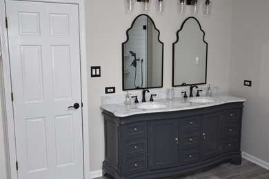 Diseño de cuarto de baño tradicional renovado de tamaño medio con armarios con rebordes decorativos, puertas de armario negras, paredes beige, lavabo encastrado, suelo gris y encimeras blancas