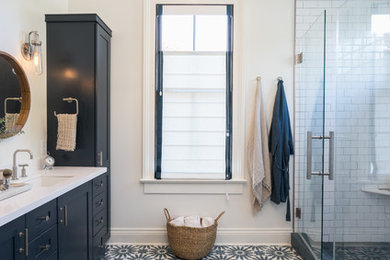 Trendy master white tile and ceramic tile cement tile floor and multicolored floor bathroom photo in New Orleans with shaker cabinets, blue cabinets, white walls, an undermount sink, quartz countertops and a hinged shower door