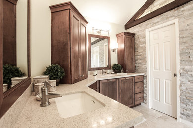 Klassisk inredning av ett stort en-suite badrum, med luckor med profilerade fronter, skåp i mörkt trä, grå kakel, stenkakel, beige väggar, travertin golv, ett undermonterad handfat, bänkskiva i kvarts och beiget golv
