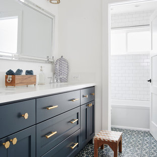 Beach style kids bathroom in San Francisco with shaker cabinets, blue cabinets, an alcove tub, white tile, subway tile, white walls, an undermount sink, multi-coloured floor, white benchtops, a shower/bathtub combo, a two-piece toilet, cement tiles, engineered quartz benchtops and a shower curtain.