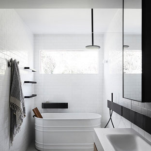 This is an example of a contemporary bathroom in Melbourne with flat-panel cabinets, dark wood cabinets, a freestanding tub, a curbless shower, white tile, subway tile, white walls, a drop-in sink, grey floor, an open shower and white benchtops.