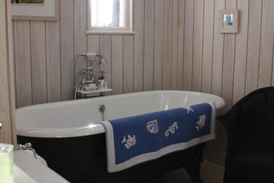 Medium sized traditional ensuite bathroom in Other with a claw-foot bath, a shower/bath combination, a one-piece toilet, grey tiles, grey walls and ceramic flooring.
