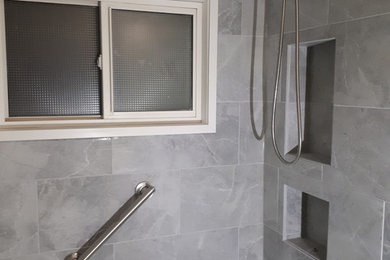Kleines Badezimmer mit weißen Schränken, Wandtoilette mit Spülkasten, grauen Fliesen, Porzellanfliesen, grüner Wandfarbe, Porzellan-Bodenfliesen, Marmor-Waschbecken/Waschtisch, grauem Boden, Schiebetür-Duschabtrennung und weißer Waschtischplatte in Edmonton