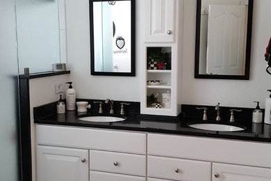 Inspiration for a mid-sized timeless 3/4 white tile ceramic tile and white floor alcove shower remodel in Richmond with raised-panel cabinets, white cabinets, white walls, an undermount sink, quartz countertops, a hinged shower door and black countertops