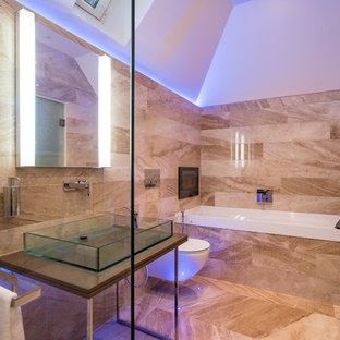 Photo of a medium sized contemporary bathroom in Buckinghamshire with an alcove bath, a wall mounted toilet, beige tiles, brown tiles, brown walls, a vessel sink, brown floors and brown worktops.