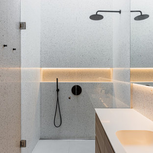 Inspiration for a modern bathroom in London with flat-panel cabinets, medium wood cabinets, a built-in shower, grey tiles, an integrated sink, grey floors, a hinged door, white worktops, a single sink and a floating vanity unit.