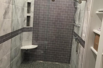 Inredning av ett modernt mellanstort badrum med dusch, med vita skåp, en dusch i en alkov, en toalettstol med separat cisternkåpa, grå kakel, tunnelbanekakel, vita väggar, klinkergolv i småsten, grått golv och dusch med skjutdörr