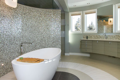 Modern inredning av ett stort en-suite badrum, med släta luckor, grå skåp, ett fristående badkar, en toalettstol med hel cisternkåpa, grå kakel, porslinskakel, grå väggar, klinkergolv i porslin, ett undermonterad handfat och bänkskiva i akrylsten
