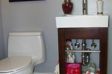 Modelo de cuarto de baño contemporáneo pequeño con armarios abiertos, puertas de armario de madera en tonos medios, sanitario de una pieza, paredes grises, suelo de baldosas de porcelana y lavabo tipo consola