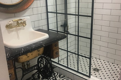 Mid-sized urban 3/4 black and white tile and subway tile porcelain tile and white floor bathroom photo in Las Vegas with furniture-like cabinets, brown cabinets, a wall-mount toilet, white walls, a drop-in sink, granite countertops and black countertops