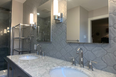 This is an example of a medium sized traditional ensuite bathroom in Philadelphia with recessed-panel cabinets, grey cabinets, an alcove shower, a two-piece toilet, grey tiles, ceramic tiles, beige walls, porcelain flooring, a submerged sink, marble worktops, grey floors, a hinged door and grey worktops.