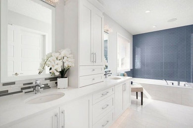 Inspiration for a large traditional ensuite bathroom in Calgary with shaker cabinets, white cabinets, a corner bath, grey tiles, white tiles, matchstick tiles, white walls, porcelain flooring, a submerged sink, solid surface worktops, a walk-in shower and beige floors.