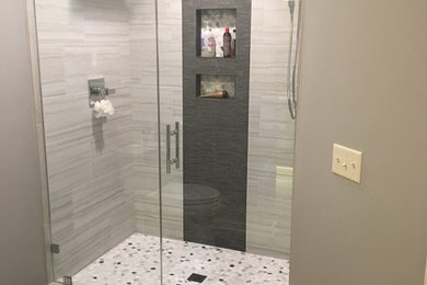 Example of a minimalist master white tile and ceramic tile ceramic tile and brown floor double shower design in Milwaukee with flat-panel cabinets, white cabinets, a wall-mount toilet, gray walls, an undermount sink, quartz countertops and a hinged shower door