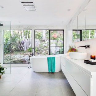 Inspiration for a large contemporary master bathroom in Sydney with raised-panel cabinets, white cabinets, a freestanding tub, an open shower, a one-piece toilet, black and white tile, ceramic tile, white walls, ceramic floors, a vessel sink, solid surface benchtops, grey floor, an open shower and white benchtops.