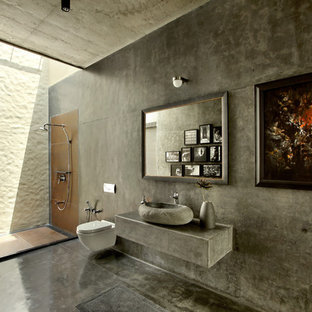 Example of an island style concrete floor bathroom design in Ahmedabad with a wall-mount toilet, a vessel sink and gray walls