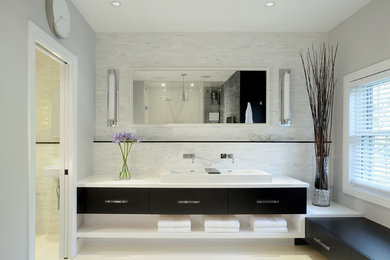 Inspiration for a modern ensuite bathroom in Toronto with a trough sink, flat-panel cabinets, dark wood cabinets, quartz worktops, a freestanding bath, a walk-in shower, a one-piece toilet, white tiles, stone tiles, grey walls and porcelain flooring.