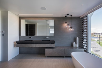 Réalisation d'une salle de bain design avec une baignoire indépendante et un carrelage gris.