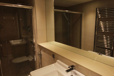 Photo of a small modern family bathroom in London with a wall-mounted sink, a built-in shower, a one-piece toilet and beige tiles.