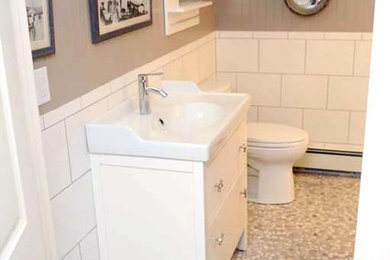Mid-sized beach style 3/4 white tile and porcelain tile pebble tile floor and gray floor bathroom photo in Boston with flat-panel cabinets, white cabinets, a two-piece toilet, gray walls, an integrated sink and solid surface countertops