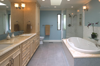 Idéer för ett stort klassiskt en-suite badrum, med skåp i ljust trä, ett platsbyggt badkar, en dusch i en alkov, en toalettstol med separat cisternkåpa, grå kakel, blå väggar, ett undermonterad handfat, granitbänkskiva, luckor med profilerade fronter, klinkergolv i porslin, grått golv och dusch med gångjärnsdörr