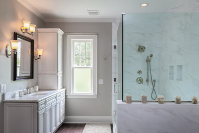 他の地域にあるコンテンポラリースタイルのおしゃれな浴室 (白いキャビネット、コーナー設置型シャワー、グレーの壁、茶色い床) の写真