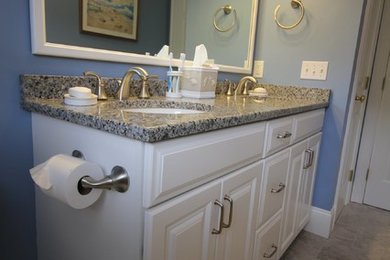 プロビデンスにある中くらいなトランジショナルスタイルのおしゃれな浴室 (レイズドパネル扉のキャビネット、白いキャビネット、青い壁、磁器タイルの床、アンダーカウンター洗面器、御影石の洗面台) の写真