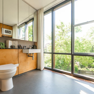 Inspiration for a medium sized retro bathroom in London with a wall-mounted sink, grey floors, a wall mounted toilet and black worktops.