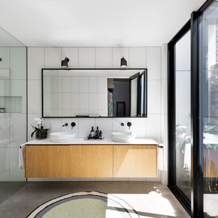 Photo of a large contemporary master bathroom in Melbourne with flat-panel cabinets, stone tile, white walls, concrete floors, engineered quartz benchtops, grey floor, an open shower, white benchtops, light wood cabinets, a curbless shower, white tile and a vessel sink.
