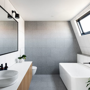 Inspiration for a mid-sized contemporary kids bathroom in Melbourne with flat-panel cabinets, a freestanding tub, gray tile, stone tile, white walls, concrete floors, engineered quartz benchtops, grey floor, white benchtops, medium wood cabinets and a vessel sink.
