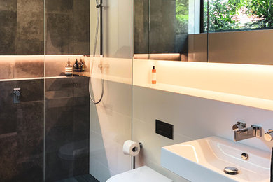 Foto di una stanza da bagno minimal con doccia a filo pavimento, WC sospeso, piastrelle grigie, piastrelle bianche, pareti bianche, lavabo sospeso, pavimento grigio e doccia aperta