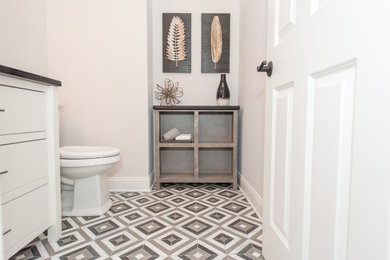 Example of a trendy mosaic tile floor, gray floor and single-sink bathroom design in Indianapolis with a one-piece toilet, white walls, an undermount sink, granite countertops and black countertops