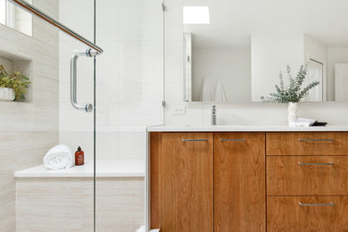 Пример оригинального дизайна: главная ванная комната среднего размера в современном стиле с плоскими фасадами, фасадами цвета дерева среднего тона, душем в нише, унитазом-моноблоком, белой плиткой, керамической плиткой, серыми стенами, полом из керамогранита, врезной раковиной, столешницей из искусственного кварца, бежевым полом, душем с распашными дверями, белой столешницей и тумбой под две раковины