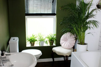 Diseño de cuarto de baño contemporáneo con bañera encastrada, combinación de ducha y bañera, sanitario de una pieza, paredes verdes, suelo de madera oscura y lavabo con pedestal