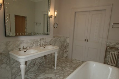 ロンドンにあるトラディショナルスタイルのおしゃれな子供用バスルーム (置き型浴槽、石スラブタイル、白い壁、大理石の床) の写真