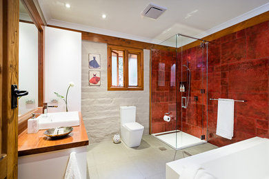 メルボルンにあるお手頃価格の中くらいなラスティックスタイルのおしゃれなマスターバスルーム (白いキャビネット、木製洗面台、コーナー設置型シャワー、一体型トイレ	、赤いタイル、セラミックタイル、赤い壁、セラミックタイルの床) の写真