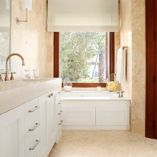 Ispirazione per una grande stanza da bagno tropicale con lavabo sottopiano, ante con riquadro incassato, ante bianche, vasca da incasso e pareti beige