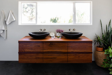 Inspiration for a large contemporary ensuite bathroom in San Diego with flat-panel cabinets, white walls, cement flooring, a vessel sink, wooden worktops, black floors, dark wood cabinets and brown worktops.