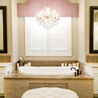 Mid-sized elegant master beige tile and stone tile marble floor drop-in bathtub photo in Las Vegas with white cabinets, raised-panel cabinets, beige walls and marble countertops