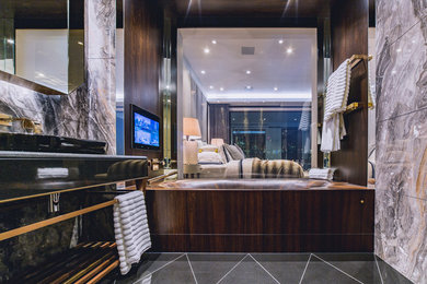 Cette image montre une salle de bain principale design de taille moyenne avec un placard à porte plane, des portes de placard noires, une baignoire en alcôve, des carreaux de céramique, un plan vasque et un plan de toilette en surface solide.