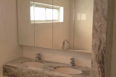 シドニーにある中くらいなおしゃれな浴室 (白いキャビネット、白い壁、大理石の洗面台) の写真