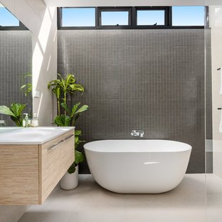 This is an example of a mid-sized contemporary master bathroom in Sydney with flat-panel cabinets, light wood cabinets, a freestanding tub, beige walls, a wall-mount sink, white benchtops, an open shower, porcelain tile, porcelain floors, beige floor and an open shower.
