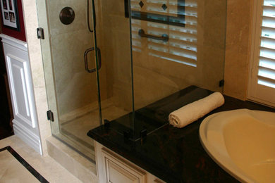 Trendy master marble floor bathroom photo in Orange County with raised-panel cabinets, white cabinets, a one-piece toilet, red walls, an undermount sink and granite countertops
