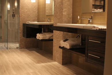 Photo of a large contemporary ensuite bathroom in Atlanta with brown cabinets, porcelain flooring, grey floors, flat-panel cabinets, an alcove shower, grey walls, a vessel sink, wooden worktops, a hinged door, travertine tiles and beige tiles.