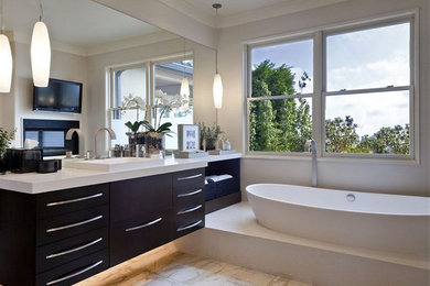 Example of a mid-sized trendy master marble floor and gray floor freestanding bathtub design in Seattle with flat-panel cabinets, dark wood cabinets, gray walls, a drop-in sink, quartz countertops and white countertops