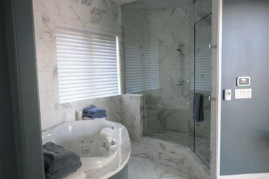 Esempio di una grande stanza da bagno padronale tradizionale con vasca freestanding, doccia ad angolo, piastrelle grigie, piastrelle di marmo, pareti grigie, pavimento in marmo, pavimento grigio e porta doccia a battente